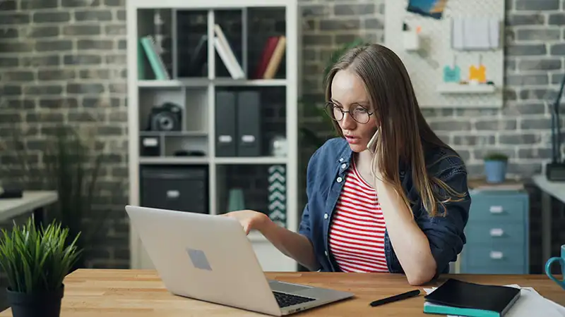 Girl talking on the phone watching laptop